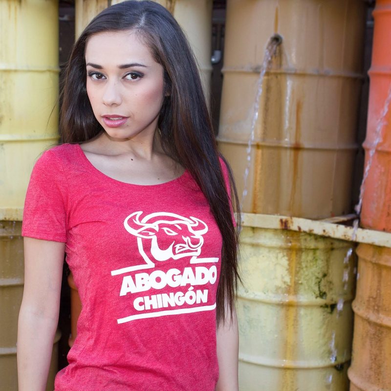 Modelo con playera roja Abogado Chingón frente a barriles de colores
