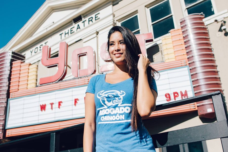 Modelo con playera azul Abogado Chingón frente a un teatro