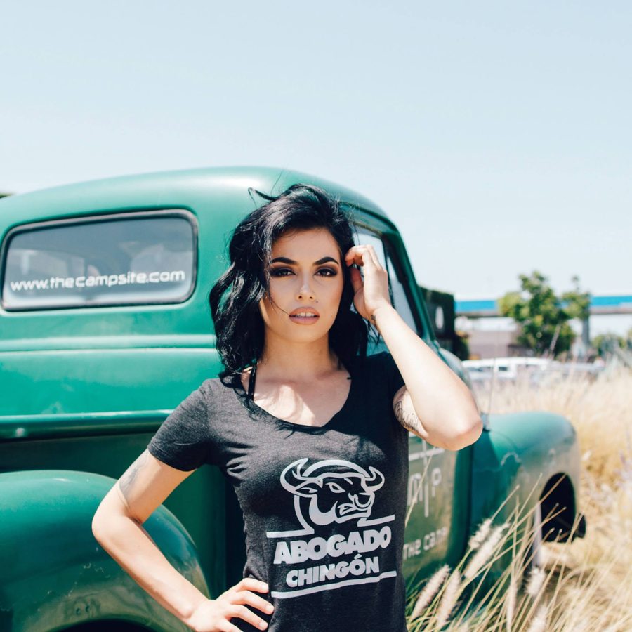 Modelo con playera negra Abogado Chingón junto a una troca clásica